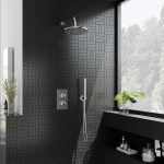 a chrome concealed shower set with a black tile background