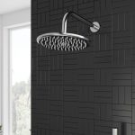 a chrome rain fall shower head and wall arm with a black tiled background