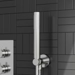 a chrome round shower head and outlet elbow with a black tiled background
