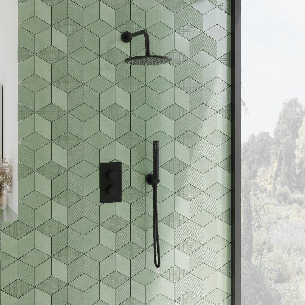 a matt black concealed shower including a round shower head and wall arm with a green tiled background