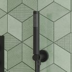 a matt black round shower head and outlet elbow with a green tiled background