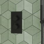 a core matt black thermostatic concealed shower valve with a green tile background