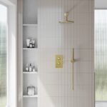 a brushed brass concealed shower set with a white tiled background